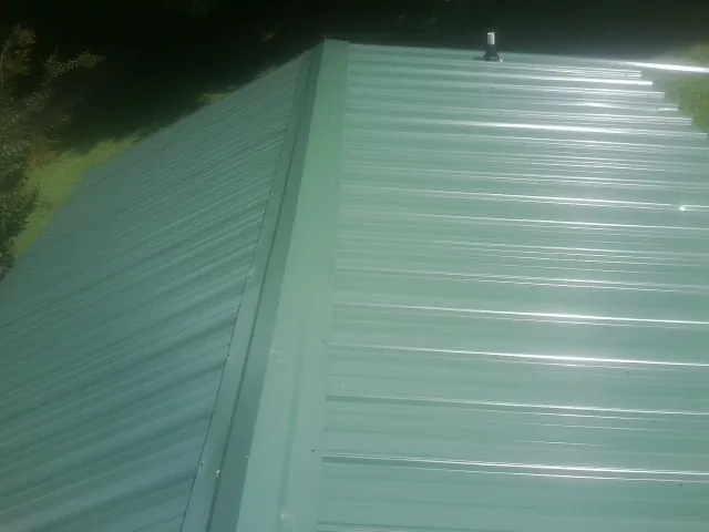 New green metal panels meeting at the ridge of a roof — Flat Roof Repair work by our crew in Three Springs