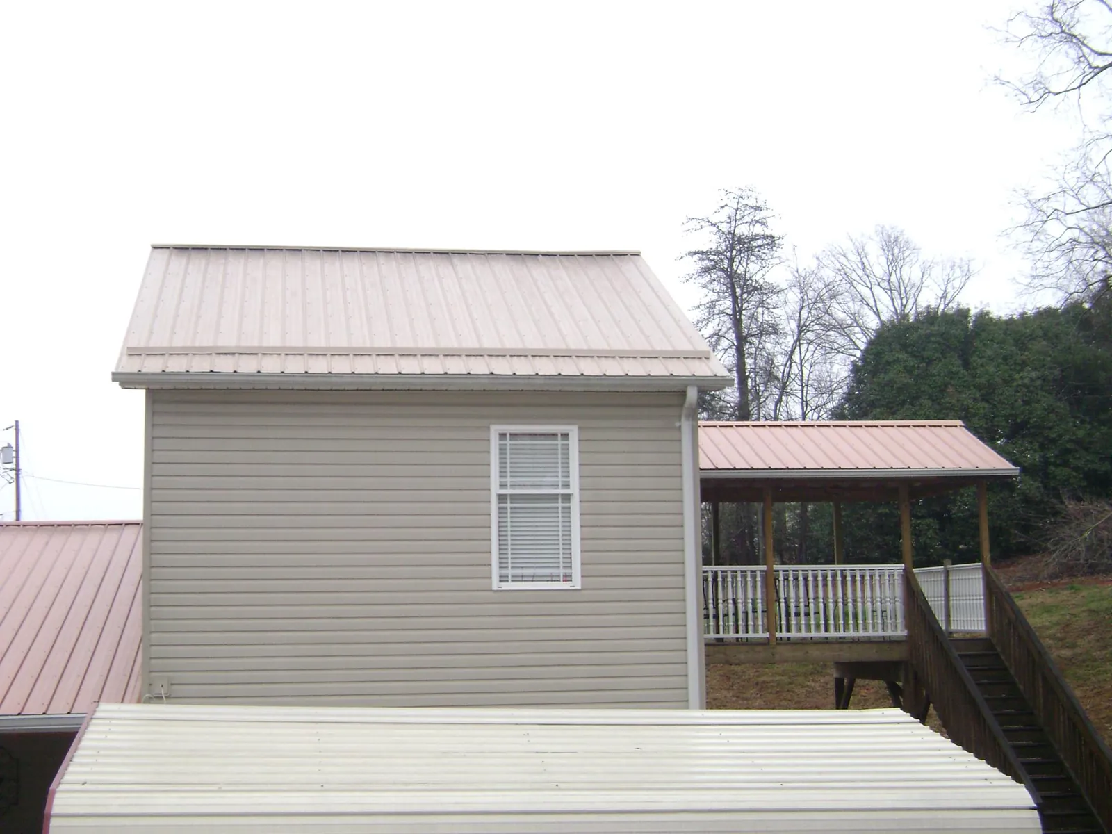 Tan metal roofs on a two story addition and attached porch, from a Roof Replacement job in Three Springs