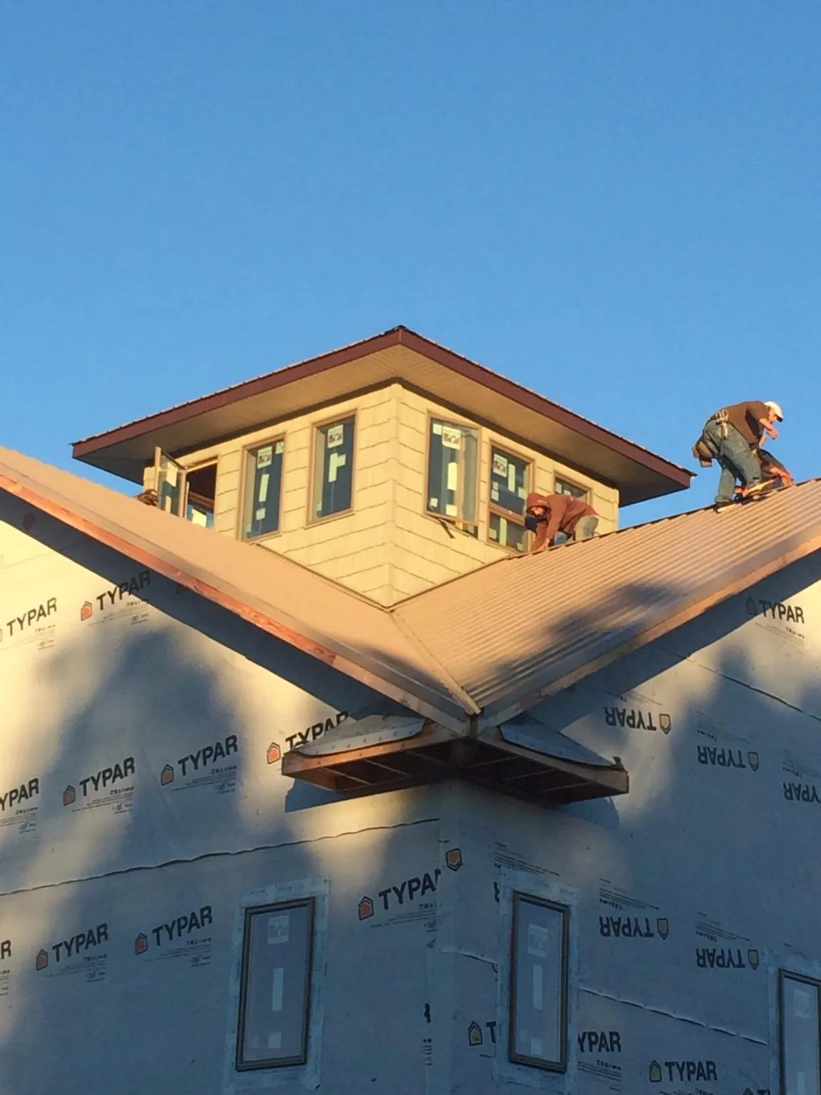 Roofers working around a rooftop cupola on a new metal roof at sunset — Roof Waterproofing in Three Springs by Roofing Brothers